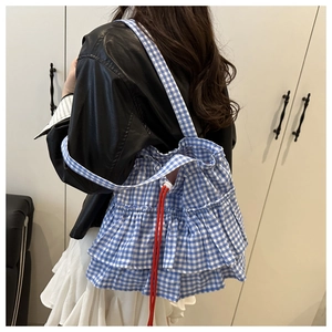 Détail du sac cabas à carreaux bleu et blanc avec volants et cordons rouges