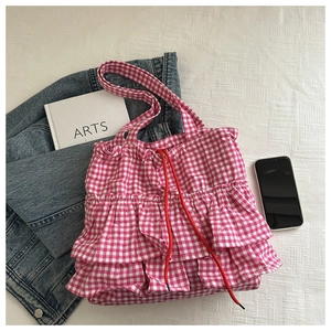 Detail of pink gingham tote bag featuring layered ruffles and red drawstring closure