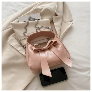 Gros plan d'un sac à main rose en similicuir avec nœud et chaîne argentée