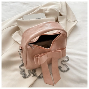 Détail du sac à main rose poudré avec décoration nœud géant et bandoulière en chaîne argent