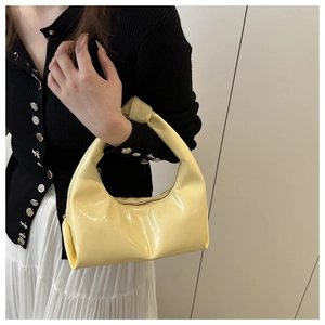 Detail of light yellow patent leather hobo bag with unique knotted handle design