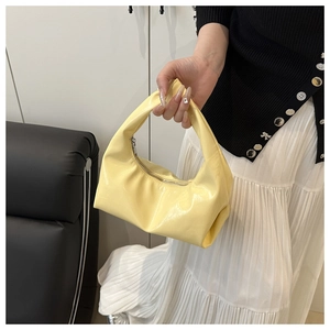 Detailed close-up of glossy pale yellow croissant bag showing patent leather and metal zipper