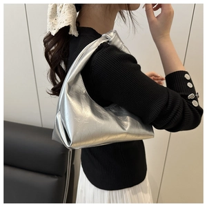 Detail of silver metallic pleated hobo bag with knotted strap shown on person