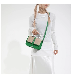 Detail of green leather handbag with straw texture flap and silver metal handle