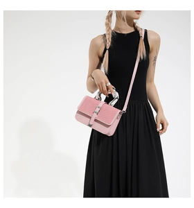 Detail of pink leather handbag showing woven texture and oversized silver metal round handle