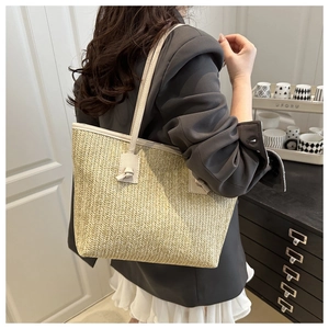 Detail of hand-woven straw tote bag featuring cream faux leather straps and knot accents
