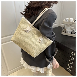 Detail of woven straw tote bag with leather straps and elegant knotted handle design