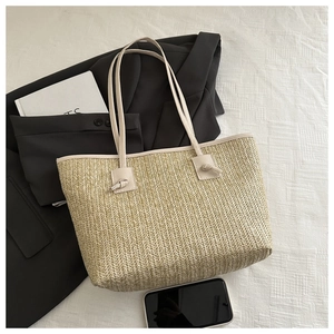 Close-up of woven straw tote bag featuring herringbone pattern and slim shoulder straps