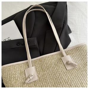 Detail of straw woven tote bag with beige litchi grain PU leather handles and knot design