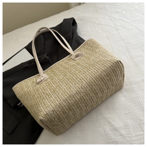 Detail of herringbone weave pattern on beige straw tote bag with knot strap detail