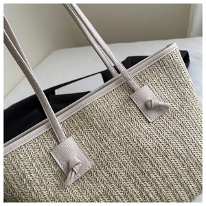 Close-up of herringbone straw weave and ivory leather knot handle detail on tote