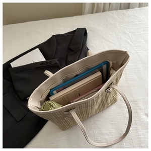Spacious beige woven tote bag showing large interior capacity with a tablet and books