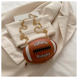 Detail of creative rugby-shaped brown crossbody bag with gold chain on beige blazer