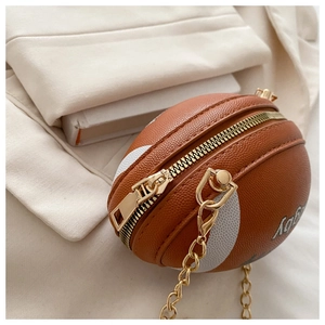 Detail of rugby-shaped crossbody bag with leather texture and gold chain strap
