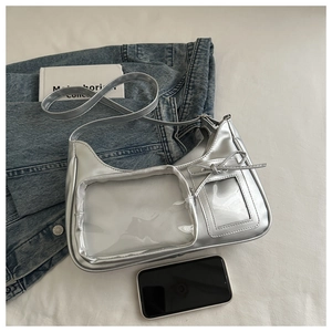 Detail of silver metallic Y2K shoulder bag featuring a transparent pocket and bow charm