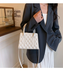 Close-up of white quilted PU leather crossbody bag with chain strap and dual handles