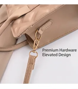 Detail shot of golden metal buckle and quilted stitching on beige shoulder bag