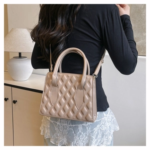 Close-up of beige quilted crossbody bag with textured embossing and top handle