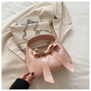 Détail du sac à main rose avec grand nœud décoratif et bandoulière en chaîne fine