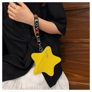Close-up of a yellow star-shaped mini bag with LOVE lettered colorful strap on a wood background