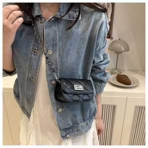 Detail of classic black quilted crossbody bag with silver chain strap on model