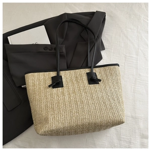Detail of hand-woven straw tote bag texture and elegant black leather knot strap