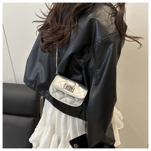 Detail of silver quilted mini crossbody bag with chain strap shown on model back