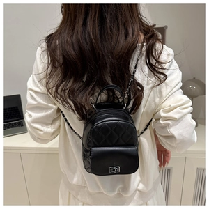 Detail of a black quilted mini backpack with silver twist lock and chain strap for women