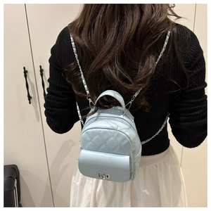 Rückansicht eines Modells mit hellblauem gestepptem Mini-Rucksack und Kettenriemen