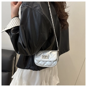 Detail view of silver quilted leather crossbody bag with chain strap on a model