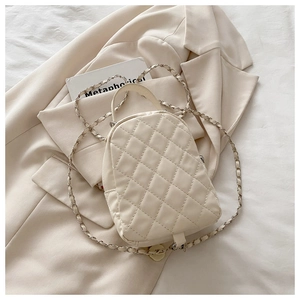 Detail of cream quilted mini backpack with chain strap on neutral suit background