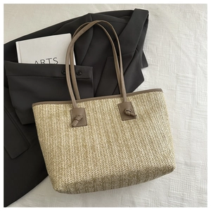 Close-up of beige straw tote bag showing fine V-shaped weaving and brown leather straps