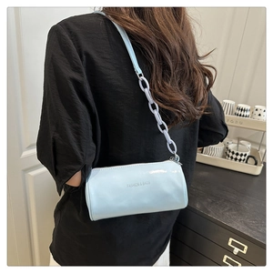 Détail du sac cylindrique bleu avec chaîne en plastique et logo texte tendance imprimé