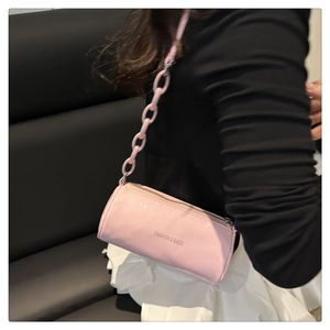 Vue détaillée du sac cylindrique rose avec bandoulière chaîne et texte gravé mode