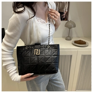 Close-up of black quilted shoulder bag with gold chain strap and metal buckle detail