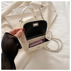 Detail of white quilted mini chain bag showing the interior pocket for lipstick