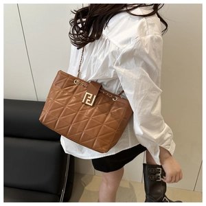 Detail of brown quilted tote bag showing geometric texture and gold chain strap