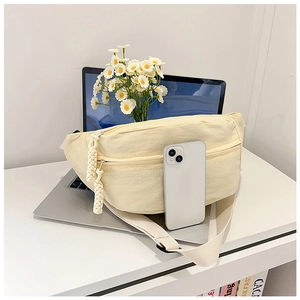Détail d'un sac bandoulière jaune crème avec tirettes de fermeture en corde tressée
