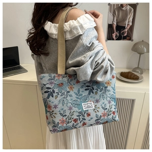 Detailed close-up of a floral jacquard tote bag with a white woven label and webbed strap