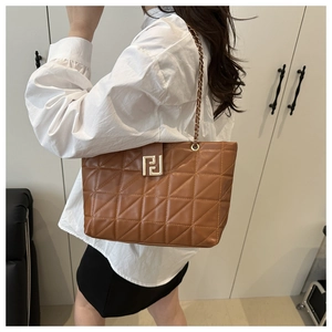 Detailed view of brown quilted tote bag with gold chain strap and geometric metal buckle