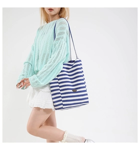 Detail of blue and white striped canvas tote bag texture with minimalist logo patch