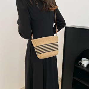 Handmade woven straw bucket bag with black stripes and brown strap for beach vacation