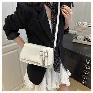 Detail view of a white leather crossbody square bag with silver chain and vertical strap accents