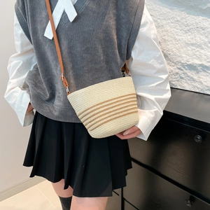 Chic beige straw crossbody bucket bag with brown stripes and leather shoulder strap