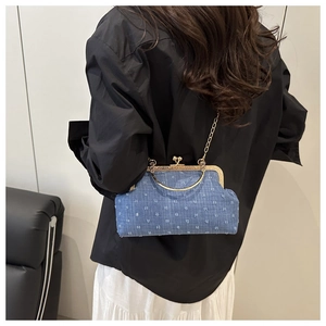 Blue denim evening clutch with white star patterns and gold metal frame on a model