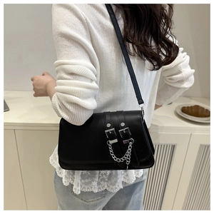 Detailed view of black crossbody bag with silver double buckles and chain on a model
