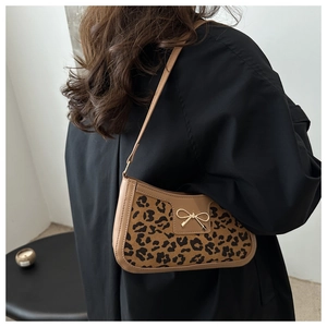 Detail of leopard print suede shoulder bag with golden bow buckle and brown leather strap