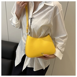 Détail du sac à bandoulière jaune en forme de croissant avec cuir lisse et logo métallique