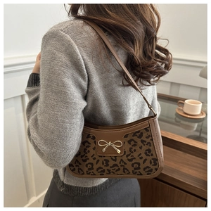 Detail showing elegant leopard print pattern with golden bow buckle on brown leather bag
