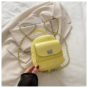 Detail of yellow quilted leather backpack with silver turn-lock and chain strap on blazer